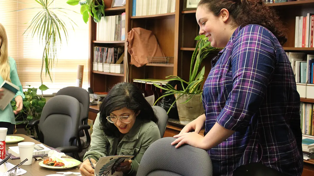 A visiting author talking with a student book club in a room lined with bookshelves